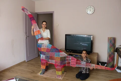 Anahita and Atbin holding a large colourful dinosaur sculpture made with a 3D pen in 2016